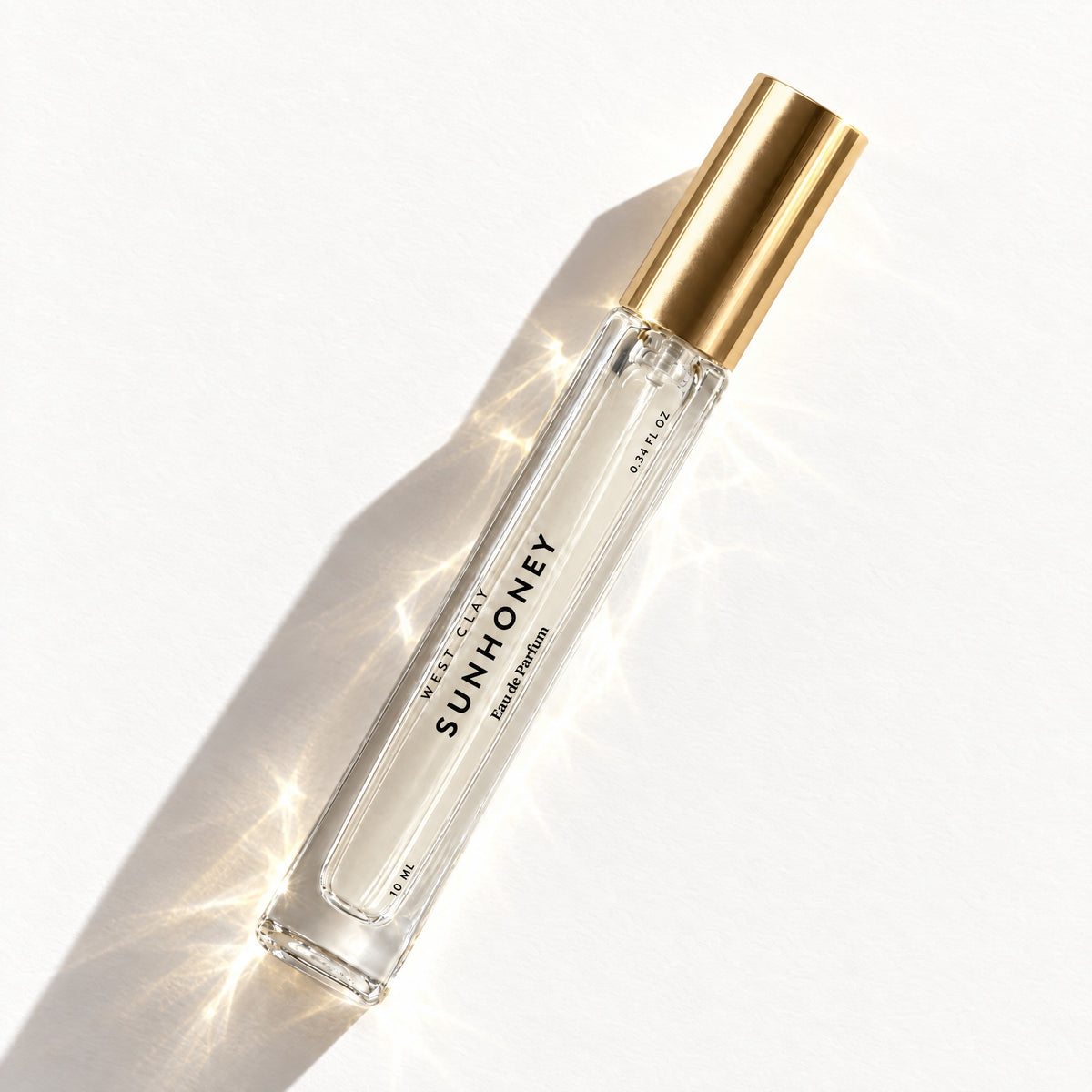 Sunhoney Eau de Parfum by West Clay, 10 mL travel size flash flat lay studio photo